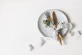 Festive table setting. Golden cutlery, berry eucalyptus branch, porcelain plate and silk ribbon on white table