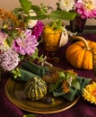 Festive table setting for Thanksgiving day. Autumnal decorations,plates, multicolor glasses and beautiful garden flowers Royalty Free Stock Photo