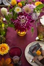 Festive table setting for Thanksgiving day. Autumnal decorations,plates, multicolor glasses and beautiful garden flowers Royalty Free Stock Photo