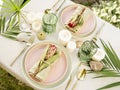 Festive table setting for two person in tropical style with flowers, candles and leaves.