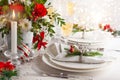 Festive table setting with winter flower arrangement on table decorated for holiday. Christmas or New Year dinner concept..