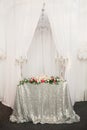 Festive table with a silver tablecloth of sequins, two candelabra with candles, a composition of flowers Royalty Free Stock Photo