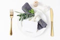 Festive table summer setting. Golden cutlery, olive branch, linen napkin, porcelain dinner plate and silk ribbon on