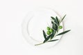 Festive table summer setting with olive leaves, branch and fruit on porcelain plate. Blank paper card mockup scene