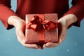 Festive touch Womans hands present a red gift with ribbon