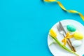 Festive traditional Easter dinner concept. Tableware, painted eggs, tulips flowers on blue table top view copy space Royalty Free Stock Photo