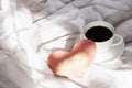 Festive Valentine\'s morning in bed. Handmade Valentine card and coffee cup on rumpled bedding