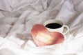 Festive Valentine\'s morning in bed. Handmade Valentine card and coffee cup on rumpled bedding