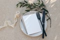 Festive wedding summer table setting. Black cutlery, olive branch, silk ribbon on dotted white dinner plate. Beige Royalty Free Stock Photo