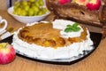 Festive white round pie with apples and whipped cream on the table. Photo of home-made baking