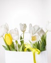 Festive white, yellow tulips composition, handmade heart, ribbon on white background. Bouquet of spring flowers in white paper bag Royalty Free Stock Photo