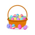 Woven Easter basket overflowing with colorful decorated eggs and scattered outside Royalty Free Stock Photo