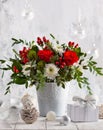 Festive winter flower arrangement with red roses, white chrysanthemum and berries in vase on table. Christmas flower composition Royalty Free Stock Photo