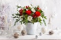Festive winter flower arrangement with red roses, white chrysanthemum and berries in vase on table. Christmas flower composition f Royalty Free Stock Photo