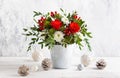 Festive winter flower arrangement in vase and Christmas baubles on table.