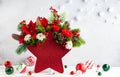 Festive winter flower arrangement in vase of red star shape and Christmas decorations on table Royalty Free Stock Photo