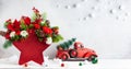 Festive winter flower arrangement in vase of red star shape and Christmas decorations on table Royalty Free Stock Photo