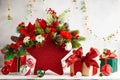 Festive winter flower arrangement in vase of red star shape and gift boxes on table. Christmas flower composition for holiday Royalty Free Stock Photo