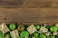 Festive wooden christmas background with golden presents and green balls.