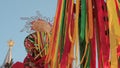 Festive wooden pole for climb on Maslenitsa. Bright ribbons fluttering in the wind on a sky background. Christmastide