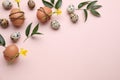 Festively decorated Easter eggs and green leaves on pale pink background, flat lay. Space for text