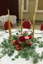 Festively decorated round banquet table in the restaurant. Fresh flowers are golden candles and garnet and red chairs. expensively Royalty Free Stock Photo