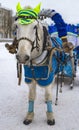 A festively dressed white horse harnessed to a painted cart