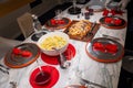 Festively set table. Silver plates on red placemats on marble top. Filet Wellington, potato salad, Cumberland sauce Royalty Free Stock Photo