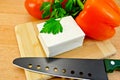 Feta cheese on a board with a knife and vegetables Royalty Free Stock Photo