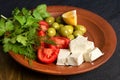 Feta cheese, tomatoes, olives and herbs in a clay plate Royalty Free Stock Photo