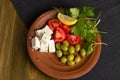 Feta cheese, tomatoes, olives and herbs in a clay plate Royalty Free Stock Photo