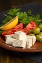 Feta cheese, tomatoes, olives and herbs in a clay plate Royalty Free Stock Photo