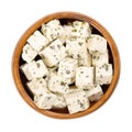 Greek feta cubes, brined cheese with Mediterranean herbs, in a wooden bowl