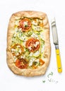 Feta, zucchini, tomatoes, thyme savory pie on a light background, top view. Delicious snack, appetizer