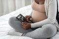 Fetal Development. Pregnant african woman looking at baby ultrasound scan at home