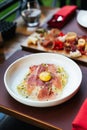 Fettuccine Carbonara with parma ham and yolk with black pepper. Served in white plate with Cold Cuts