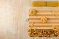 Fettuccine and Farfalle are laid out on a bamboo cutting Board and with other macaroni on a wooden background