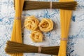 Fettuccine pasta in a frame of two types of spaghetti on a white and blue textured background Royalty Free Stock Photo