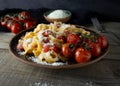 Fettuccine pasta sprinkled with parmesan cheese with a fried sprig of cherry tomatoes on a clay plate on a wooden table Royalty Free Stock Photo