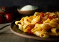 Fettuccine pasta with tomato sauce on a clay plate, shot in a low key. Cherry tomatoes and grated parmesan cheese on background Royalty Free Stock Photo