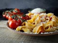 Fettuccine pasta with tomato sauce, fried cherry tomatoes, parmesan cheese on a wooden table shot in low key Royalty Free Stock Photo