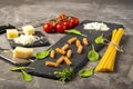 Fettuccine and spaghetti with ingredients for cooking pasta, tomato, arugula on black rock plate. Royalty Free Stock Photo