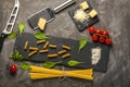 Fettuccine and spaghetti with ingredients for cooking pasta, tomato, arugula on black rock plate. Royalty Free Stock Photo