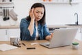 Feverish lady with pills looking at laptop webcam in kitchen