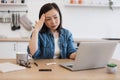 Feverish lady with pills looking at laptop webcam in kitchen