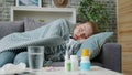 Feverish young woman checking body temperature lying on couch at home