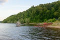 few boats on the shore and a small ship on the river in the summer