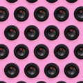 A few camera lenses with a closed aperture lie on texture background of fashion pastel pink color paper in minimal concept.
