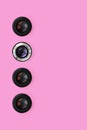 A few camera lenses with a closed aperture lie on texture background of fashion pastel pink color paper in minimal concept.