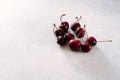 A few chilled fresh cherries lie on a light stone surface Royalty Free Stock Photo